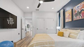 Une chambre à coucher moderne avec un lit, un ballon d’exercice et des œuvres d’art accrochées au mur.