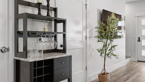 Un couloir moderne avec une console en bois foncé, une plante en pot et une porte dotée d’un miroir.