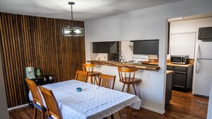 Una cocina compacta con una mesa y sillas de madera, un microondas y un refrigerador.