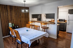Eine kompakte Küche mit Holztisch und Stühlen, einer Mikrowelle und einem Kühlschrank.