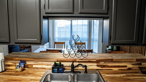 Una cocina con encimera de madera, un lavamanos doble y armarios arriba.