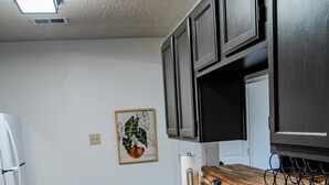 Una cocina con armarios oscuros, encimera de madera, pileta de acero inoxidable y un cubo de basura.