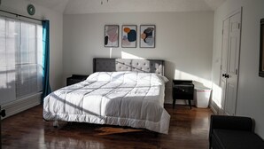 Un dormitorio con cama, ventilador de techo, ventana con persianas, mesita de noche y puerta.