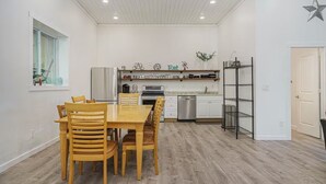 A modern kitchen with white cabinets, a wooden dining table, and a built-in oven. - Enjoyable 4 Bedroom on M22 - Close to Traverse City & Suttons Bay (Traverse City)