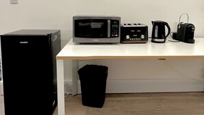 Ett kök med ett kylskåp, en mikrovågsugn, en brödrost och en kaffebryggare placerade på en vit bänkskiva.