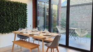 A modern dining area with a wooden table, grey chairs, and a green wall. - Shoreditch Apartments by PrimeCityHosts F11 (Greater London)