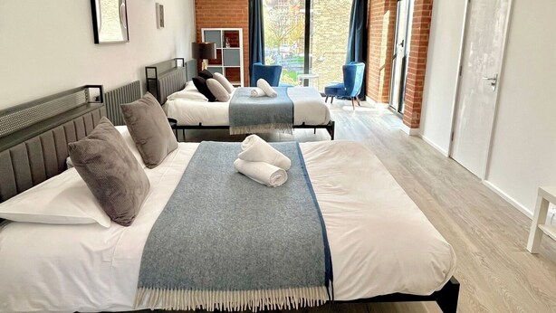 A hotel room with two beds, a view of the city, and a brick wall. - Shoreditch Apartments by PrimeCityHosts F11 (Greater London)