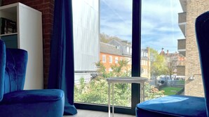 A modern living room with two blue armchairs, a white bookshelf, and a small table. - Shoreditch Apartments by PrimeCityHosts F11 (Greater London)