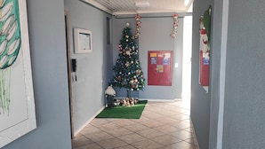 Un corridoio con pavimento piastrellato, un albero di Natale e un bacheca rossa.