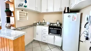 Una cucina compatta con mobili bianchi, un piano di lavoro in granito, un forno a incasso e un frigorifero.