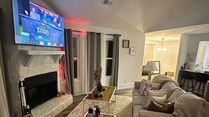 Ein Wohnzimmer mit Kamin, Fernseher, Couchtisch und Sofa.