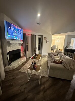 Ein Wohnzimmer mit Kamin, Fernseher, Couchtisch und Sofa.