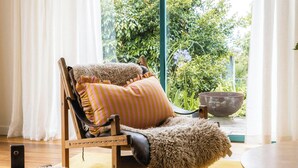 Ein gemütlicher Sessel mit weichem Sitz und Rückenlehne, platziert in der Nähe eines Fensters mit Blick ins Grüne.