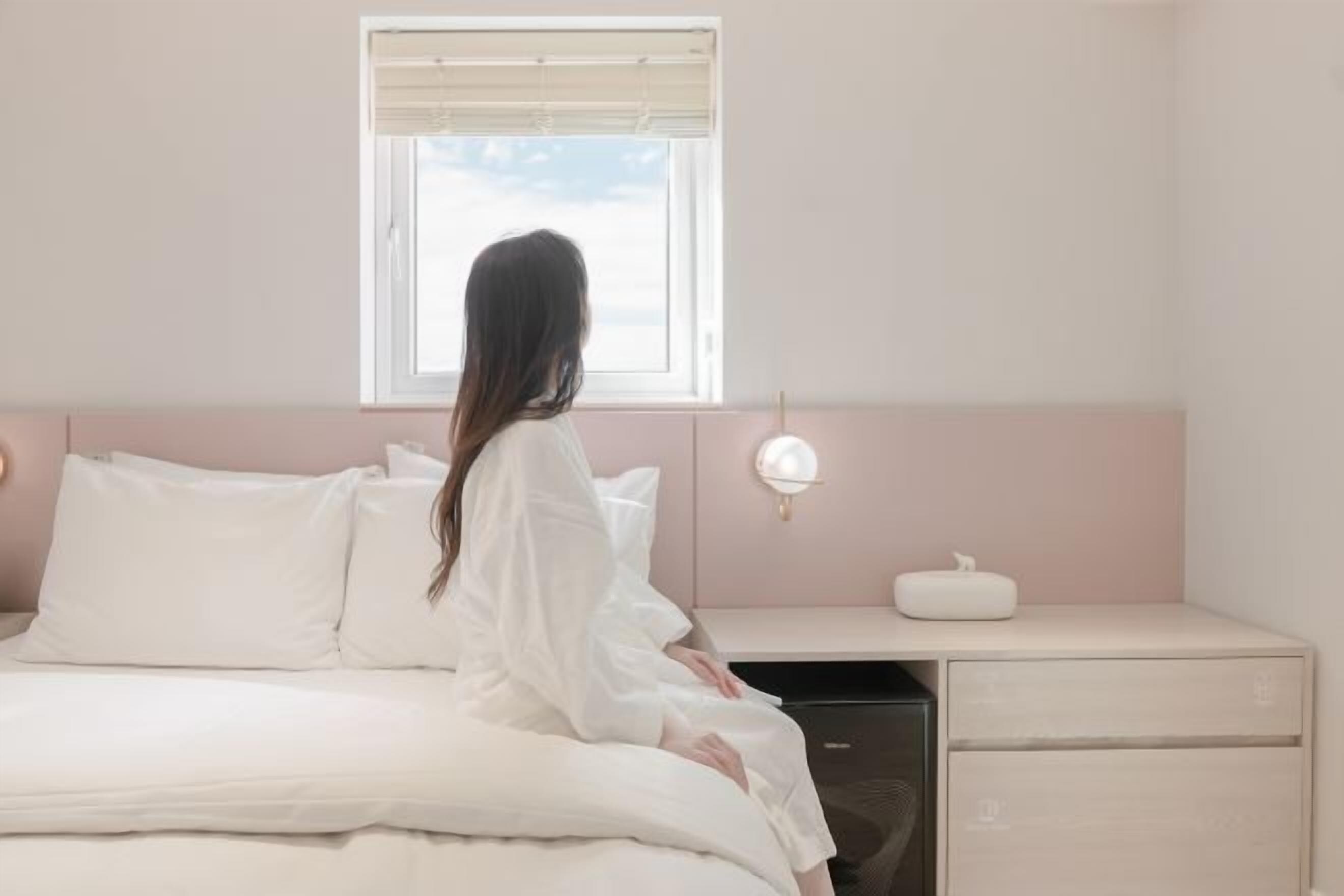 A bedroom with a bed, a bedside table, a nightstand, and a window.