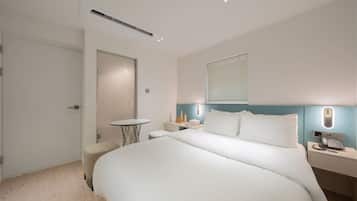 A modern hotel room with a large bed, bedside table, and a small round table.