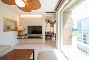 Een moderne woonkamer met een open haard, een televisie en een eethoek met stoelen.