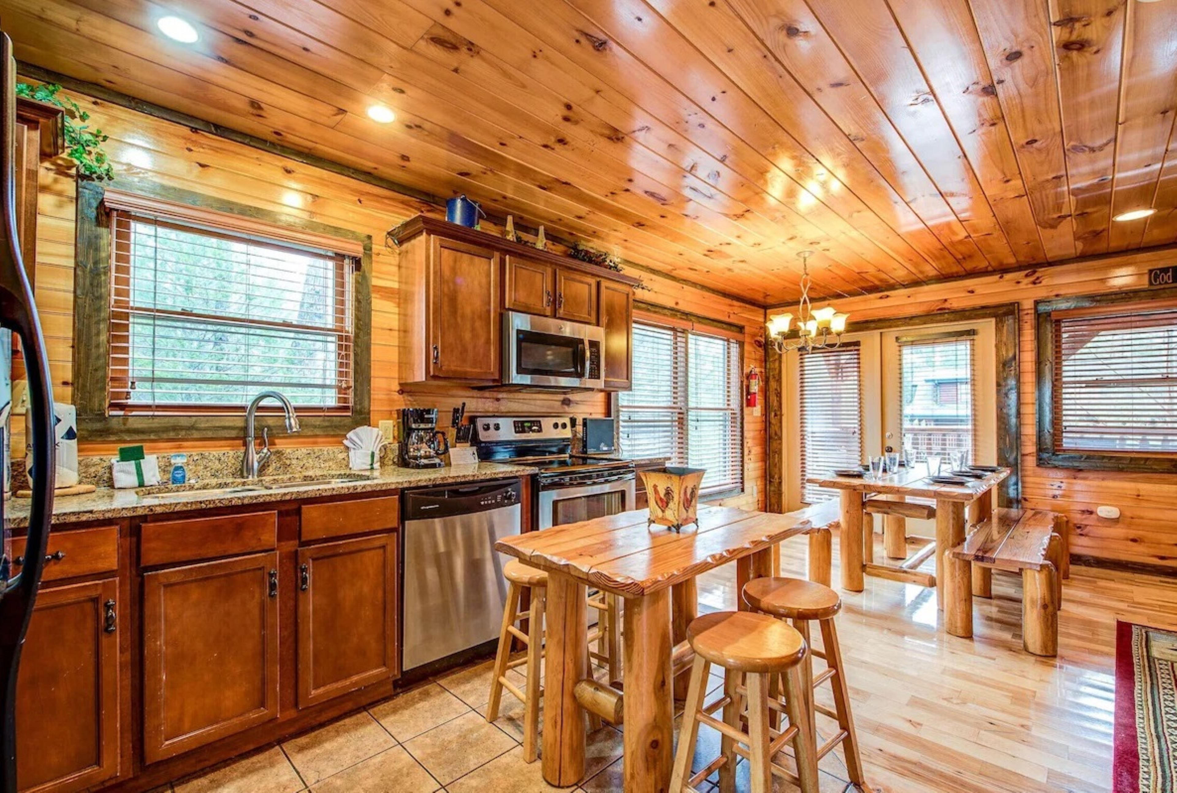 Una cocina tipo cabaña de madera con una isla central, electrodomésticos integrados y ventanas amplias.