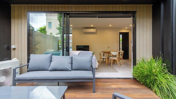A modern outdoor living area with a sofa, a dining table, and chairs. - Central City House with Garage | Walk to Stadium (Christchurch)