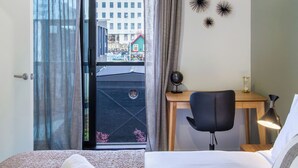 Een hotelkamer met een bed, een bureau, een stoel en uitzicht op een gebouw.