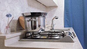 A kitchen with a gas stove, a pot on the stove, a sink, and a blue curtain. - 북한산이 가깝고  , 명동 까지 40분. 조용하고 편안한 숙소. (Seoul)