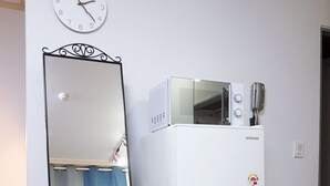 A compact kitchenette with a white refrigerator, microwave, and a small oven. A full-length mirror is positioned to the left, reflecting part of the room. - 북한산이 가깝고  , 명동 까지 40분. 조용하고 편안한 숙소. (Seoul)