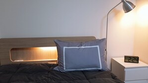 A neatly made bed with a gray pillow and a wooden headboard, a bedside lamp, and a digital clock displaying 2:24. - 북한산이 가깝고  , 명동 까지 40분. 조용하고 편안한 숙소. (Seoul)
