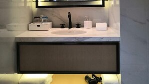 A modern bathroom with a large mirror, a sink, and a vanity with a towel and headphones on it. - The Hotel V Hongqiao  (Shanghai)