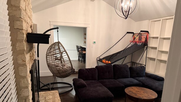 A modern living room with a sectional sofa, a hanging chair, a small round table, and a hammock.