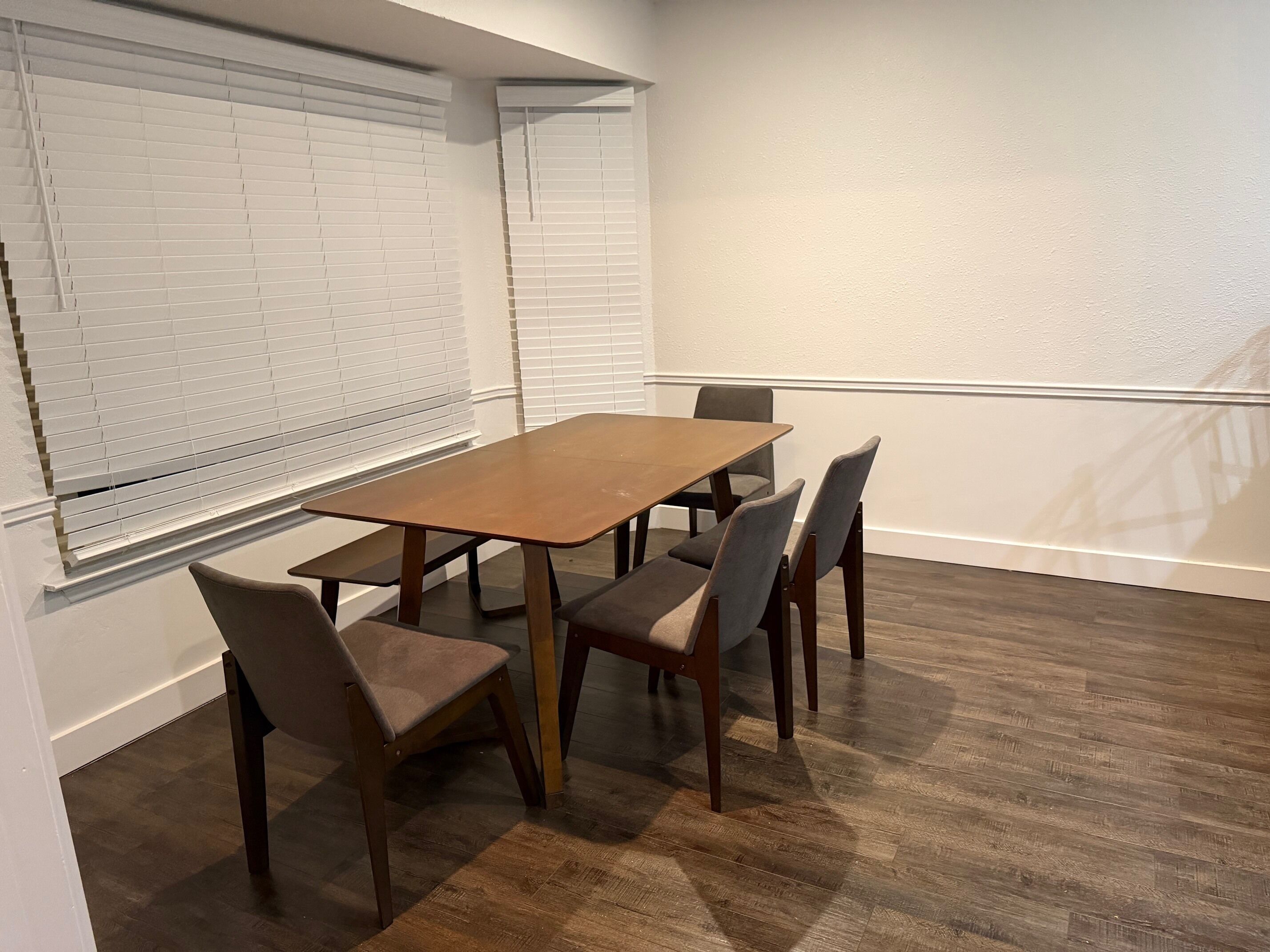Une salle de conférence avec une table en bois et six chaises, des murs blancs et un plancher en bois.