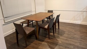 A conference room with a wooden table and six chairs, white walls, and a wooden floor.