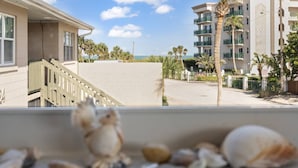Ein Strandhotel mit Meerblick, ein Balkon mit Muscheln und Palmen.