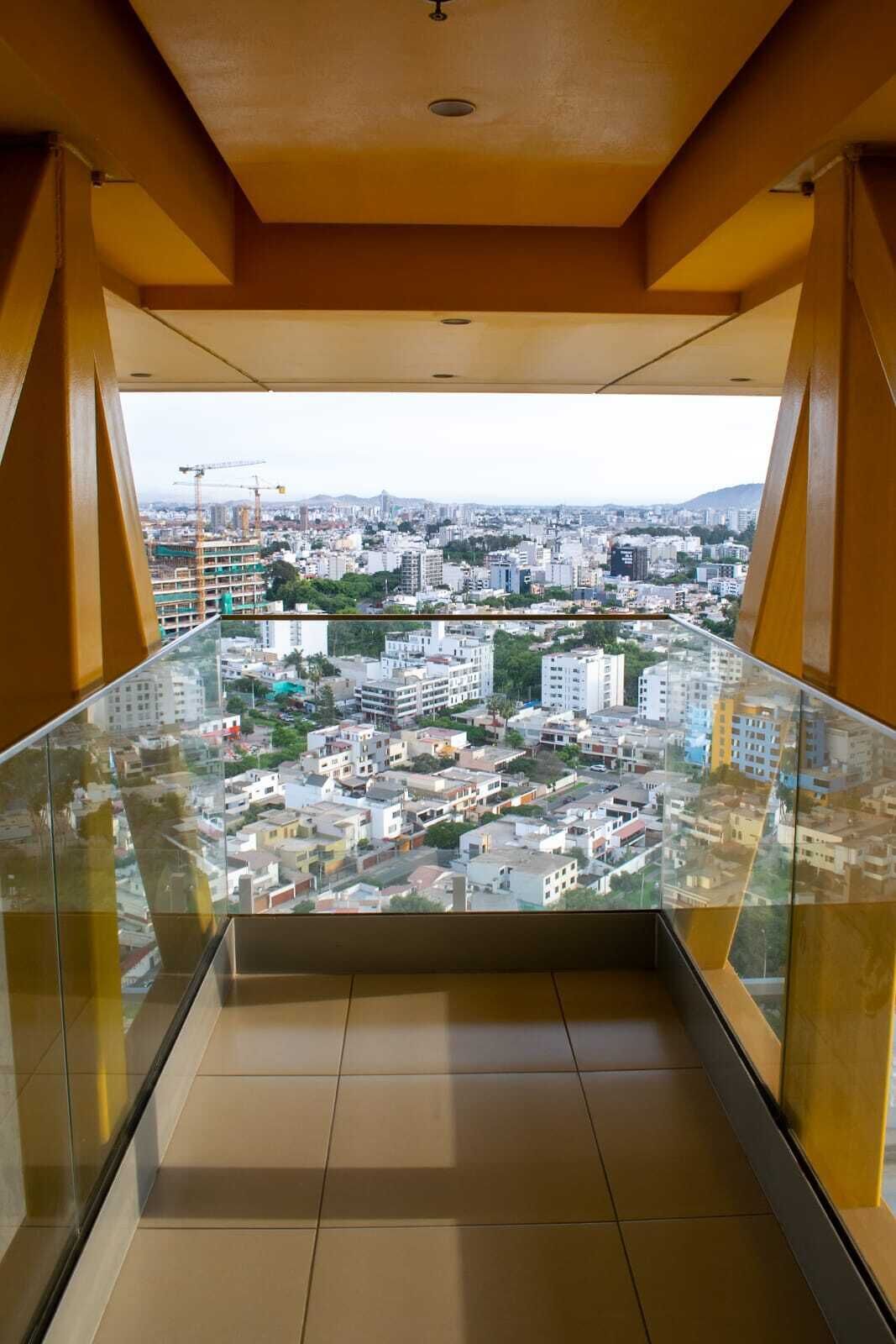 A high-rise building with a glass balcony offering a city view.