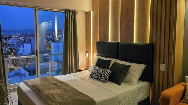 Una camera da letto con un letto grande, vista sulla città e arredamento moderno con pannelli in legno.