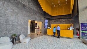 Un'area reception dal design moderno, con scrivania, zona relax e parete display digitale.