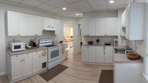 A modern kitchen with white cabinetry, a microwave, stove, and a sink. - Stylish 3BR Revere Home|Sleeps 8|Near Boston&Beach (Revere)