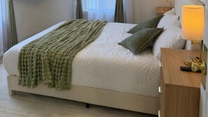 A neatly arranged bedroom with a bed, bedside lamps, a flat-screen TV, and a painting on the wall. - Stylish 3BR Revere Home|Sleeps 8|Near Boston&Beach (Revere)