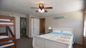 Un dormitorio con una cama litera, una cama individual, un ventilador de techo y una decoración de peces en la pared.