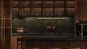 Une cuisine moderne avec des meubles en bois, un plan de travail noir et trois tabourets.