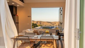 A dining area with a table and chairs, a sofa, and a view of a landscape. - NEW: Sol + Shadow | Pool | Spa | Walk to Downtown (Joshua Tree)