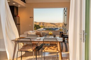 Ein Essbereich mit Tisch und Stühlen, einer Couch und Blick auf eine Landschaft.
