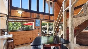 Un intérieur en bois comprenant un coin repas, un escalier et de grandes fenêtres.