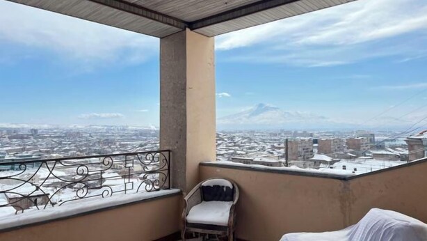 Een balkon met uitzicht op een stadsbeeld en bergen.