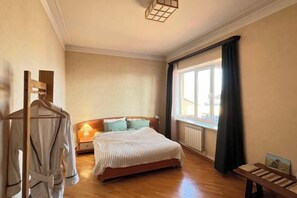 A bedroom with a bed, a nightstand, a lamp, a window with curtains, and a wooden bench. - Noah’s sunlight villa hotel (Yerevan)
