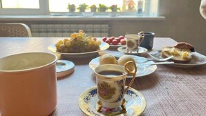 Een gedekte tafel met een kop koffie, een bord met druiven, een bord met aardbeien en een bord met gebak.