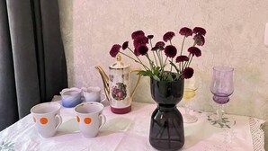Een tafel met een koffiezetapparaat, een theepot, een vaas met bloemen en twee kopjes.