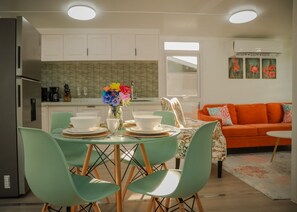A modern kitchen with white cabinets, a stainless steel refrigerator, and a dining area with a round table, green chairs, and white plates. - Cozy 2BR Villa• Private Pool and Patio• Hot water• Aruba Tropical Getaway (Oranjestad)