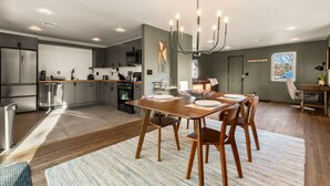 Una cocina moderna con electrodomésticos de acero inoxidable, un comedor con mesa y sillas de madera y una araña.