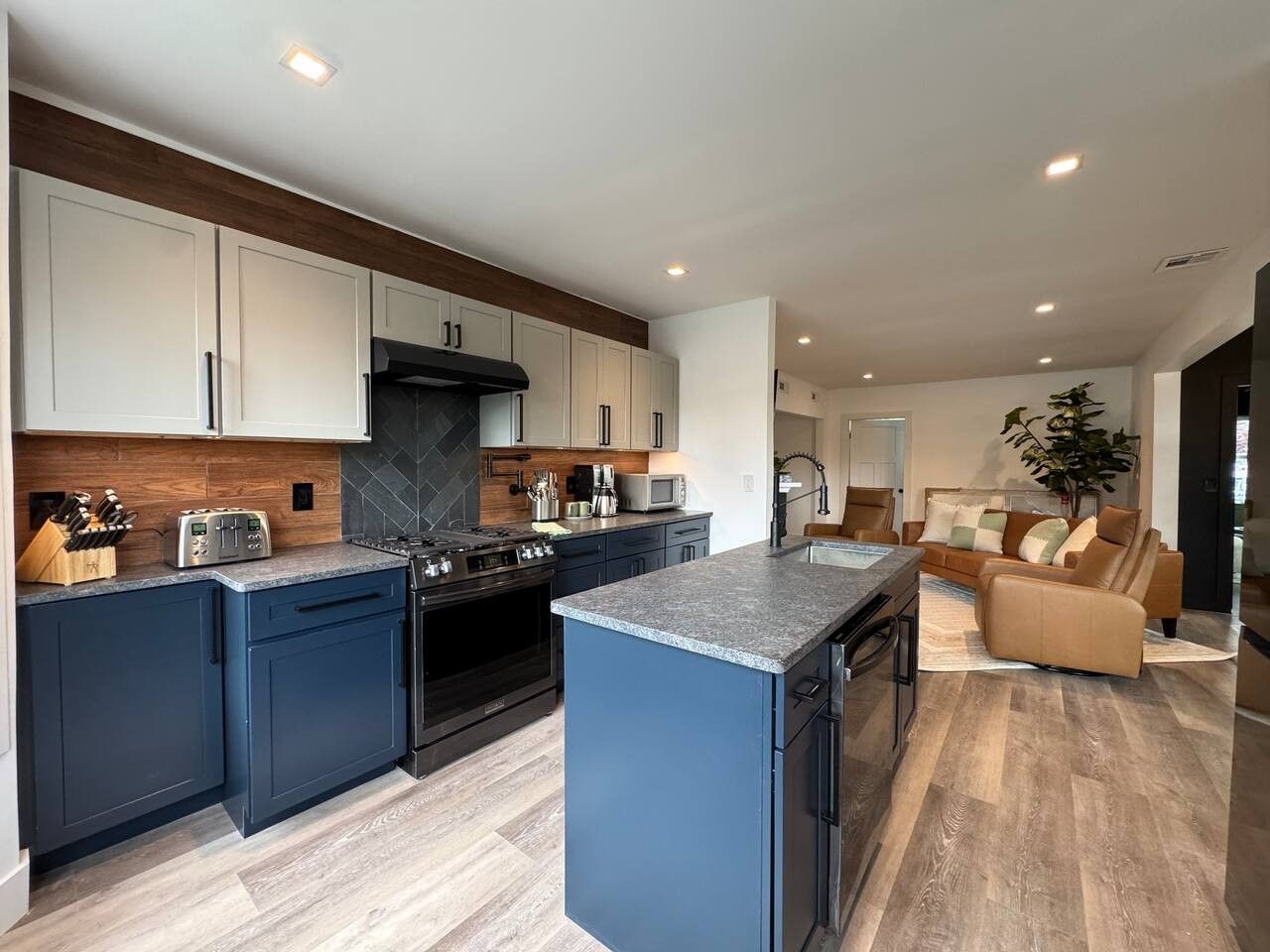 A modern kitchen with dark blue cabinets, a central island, and a built-in oven.