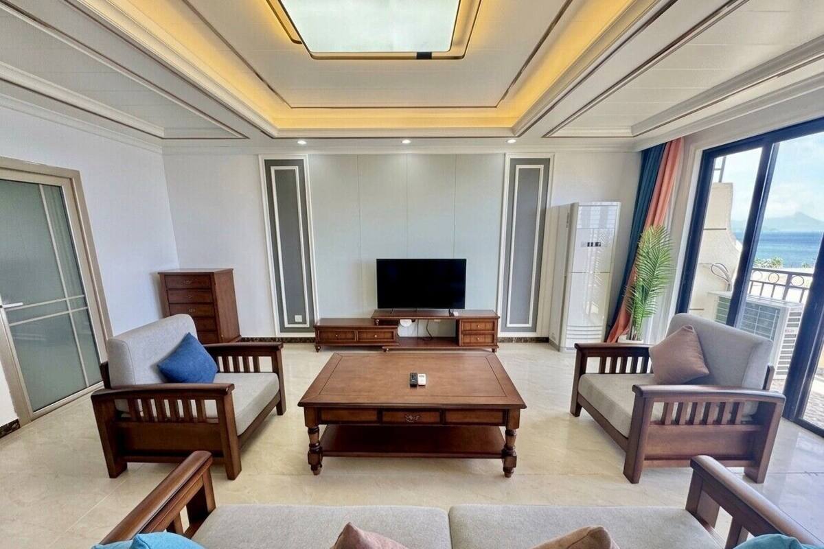 Ein großzügiges Wohnzimmer mit einem großen Flachbildfernseher, Holzmöbeln und einem Balkon mit Blick.