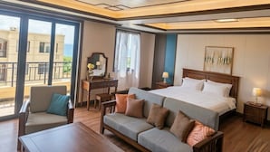 A hotel room with a large bed, a sofa, a desk, and a balcony with a view. - Seaview Garden Hotel & Residences (Basseterre)